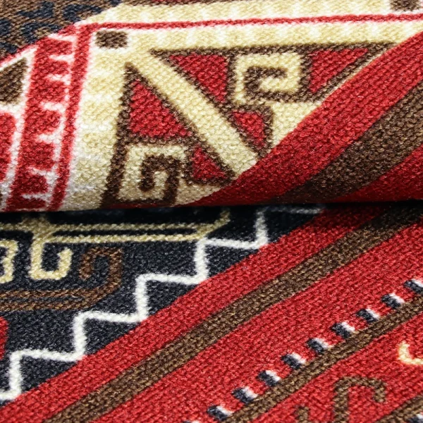 Close-up of folded patterned rug showing red, black, beige geometric motifs and woven texture.