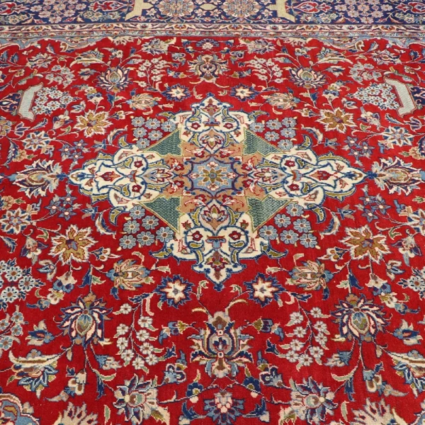 Red Persian rug with an ornate central medallion and blue, cream, and green floral patterns surrounding it.