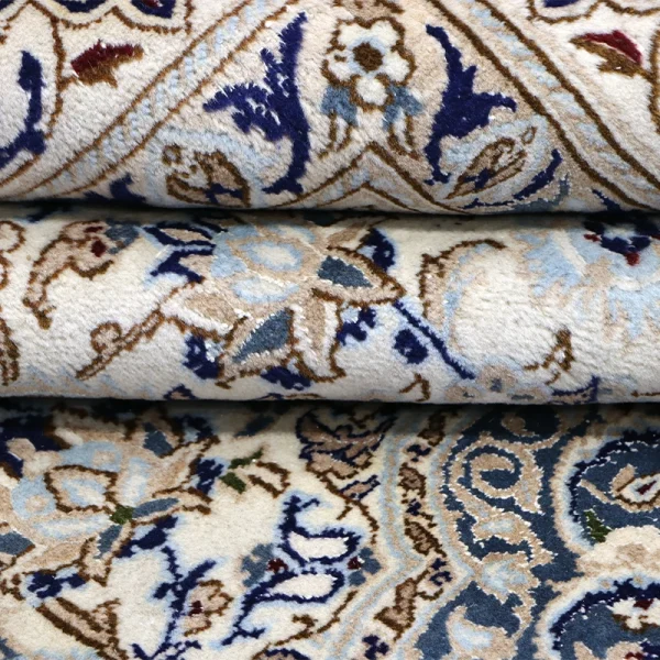 Close-up of rolled oriental carpets with blue, beige, and brown floral patterns.