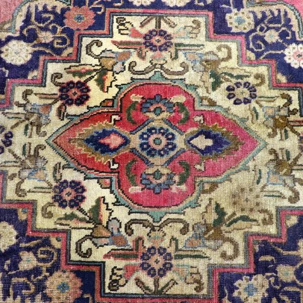 Decorative oriental rug with a central pink medallion, cream field, and blue borders featuring floral motifs.