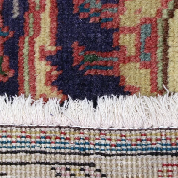 Close-up of a multicolored woven rug with white fringe along the edge.