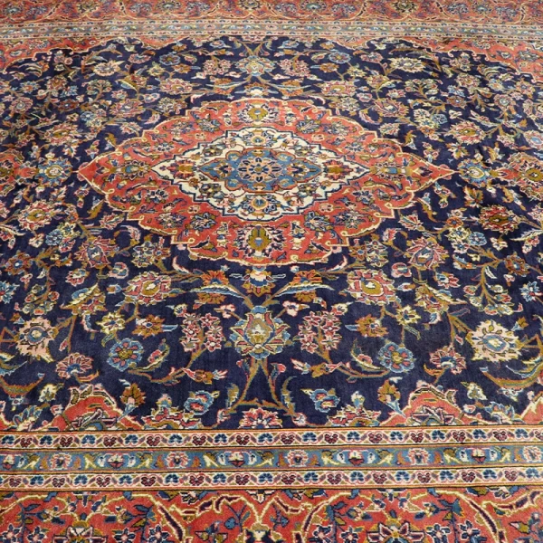 Intricately patterned Persian-style rug with a blue field, central red-and-blue medallion, and floral borders.